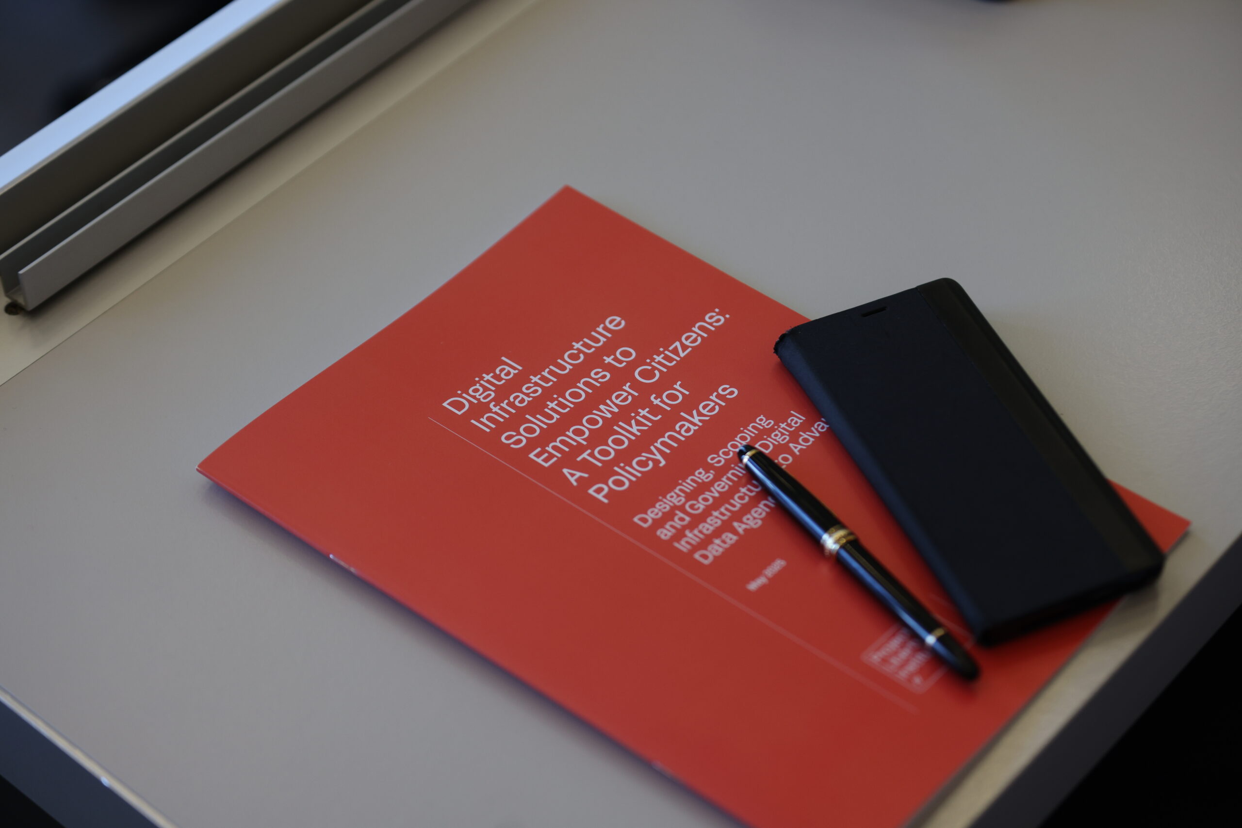 New Toolkit Launches to Equip Policymakers for Digital Infrastructure That Empowers Citizens. Photo of the report at someone's table at the Global Solutions Initiative Summit.